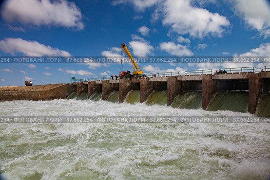 Small Aral Sea Kok-aral dam.Water discharge in flood. Open gates. Yellow mobile crane and workers on dam. Стоковое фото, фотограф Alexey Rezvykh / Фотобанк Лори