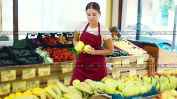 Smiling girl seller is showing assortment of fresh apples in vegetable shop. Стоковое видео, видеограф Яков Филимонов / Фотобанк Лори