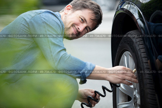 smiling man inflated rubber tires of his car. Стоковое фото, агентство Ingram Publishing / Фотобанк Лори