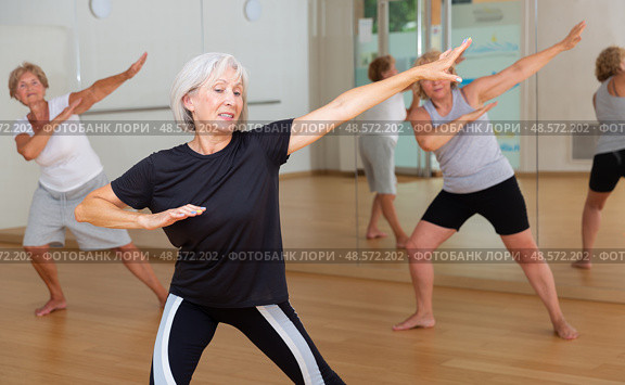 Smiling mature woman enjoying active dancing in dance studio. Стоковое фото, фотограф Яков Филимонов / Фотобанк Лори