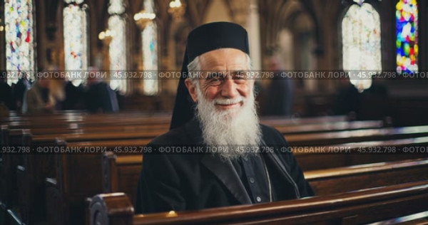 Smiling old christian priest inside church. Стоковое AI-видео, аниматор Александр Довянский / Фотобанк Лори