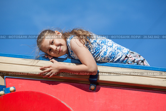 Smiling ten years old girl on red construction of children playground against blue sky. Стоковое фото, фотограф Кекяляйнен Андрей / Фотобанк Лори
