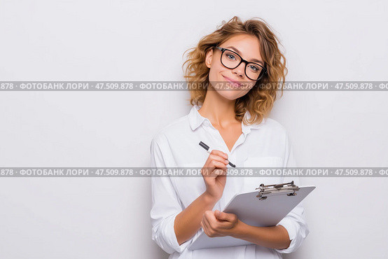 Smiling young woman holding clipboard and pen in bright office setting. Улыбающаяся молодая женщина держит в руках планшет и ручку в светлом офисном помещении. Стоковое AI-изображение, AI-художник Katsiaryna Repich / Фотобанк Лори