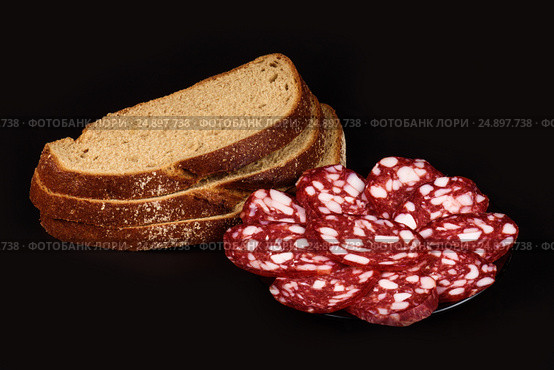 Smoked sausage and bread on a black background. Стоковое фото, фотограф Artem Sobov / Фотобанк Лори