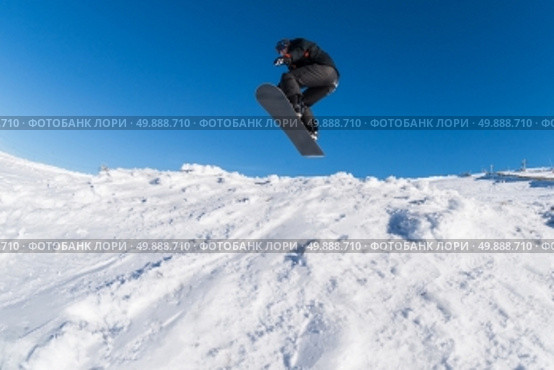 Snowboarder executing a radical jump against blue sky. Стоковое фото, агентство Ingram Publishing / Фотобанк Лори