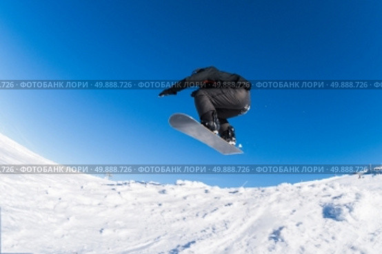 Snowboarder executing a radical jump against blue sky. Стоковое фото, агентство Ingram Publishing / Фотобанк Лори