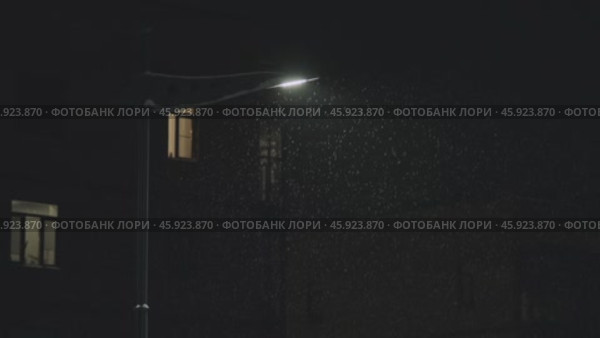 Snowfall on the background of a lantern in winter at night. Стоковое видео, видеограф Георгий Мякишев / Фотобанк Лори