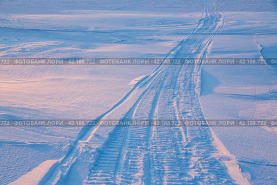 Snowmobile tracks in the snow. Snowmobiling on the ice of the frozen sea. Travels and expeditions to the far north to the Arctic. Extreme tourism in the polar region. Cold frosty winter weather. Стоковое фото, фотограф Андрей Степанов / Фотобанк Лори