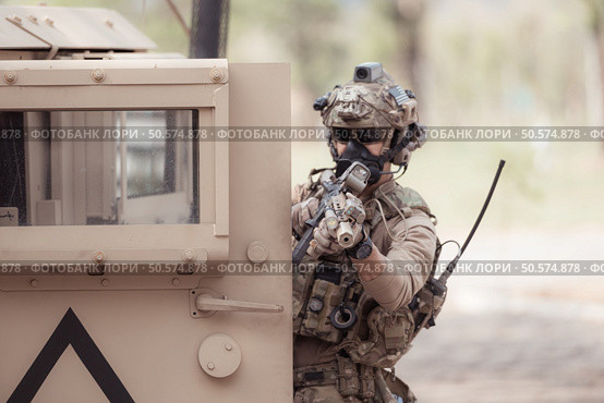 Soldiers in camouflage uniforms hold weapons ready to fire, By hiding on the side military communication vehicle. Стоковое фото, агентство Ingram Publishing / Фотобанк Лори
