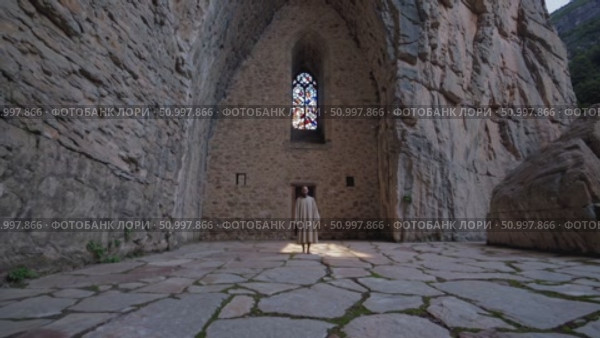 Solitary monk standing within medieval stone church, sunlight filtering through stained glass, radiating contemplative spiritual atmosphere. Стоковое AI-видео, аниматор Данил Руденко / Фотобанк Лори