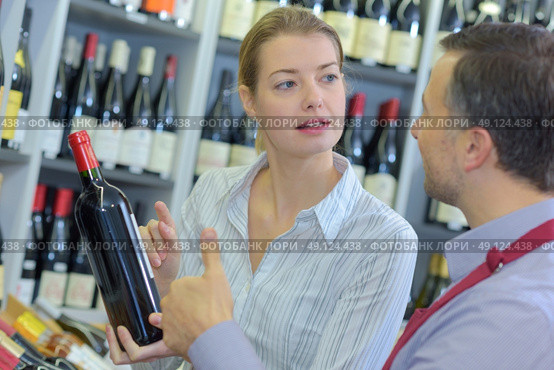 sommelier giving woman recommendation for bottle of wine. Стоковое фото, агентство Ingram Publishing / Фотобанк Лори