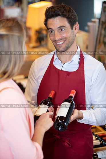 sommelier in wine store giving woman recommendation for wine. Стоковое фото, агентство Ingram Publishing / Фотобанк Лори