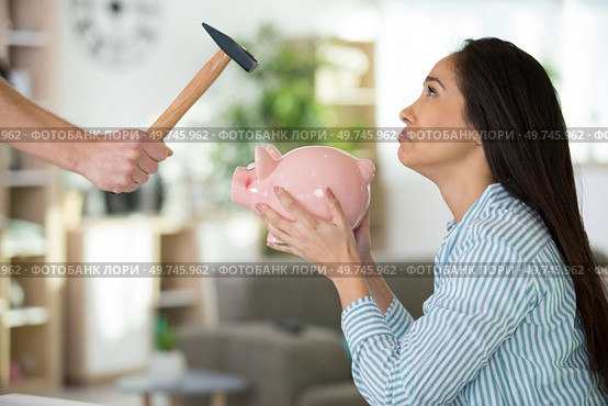 sorrowful woman not wanting to smash her piggybank. Стоковое фото, агентство Ingram Publishing / Фотобанк Лори