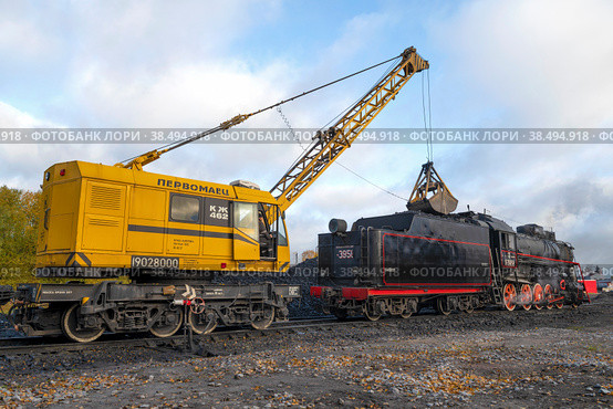SORTAVALA, RUSSIA - OCTOBER 09, 2022: Railway crane KZh-462 "Pervomaets" loads coal old Soviet steam locomotive in Sortavala station on October morning. Редакционное фото, фотограф Виктор Карасев / Фотобанк Лори