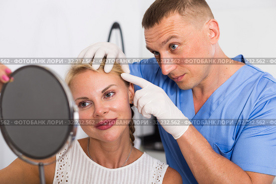 Specialist is analysing skin of female patient with using mirror before the procedure. Стоковое фото, фотограф Яков Филимонов / Фотобанк Лори