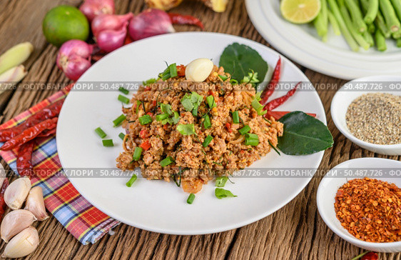 Spicy Minced Pork Salad on a white plate with red onion, lemon grass, garlic, yardlong beans, kaffir lime leaves, and spring onion. Стоковое фото, агентство Ingram Publishing / Фотобанк Лори