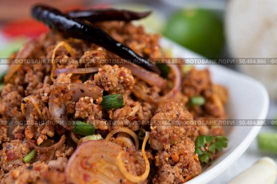 Spicy pork chops in a white dish consisting of lemons, chilies, and side dishes. Selective focus. Стоковое фото, агентство Ingram Publishing / Фотобанк Лори
