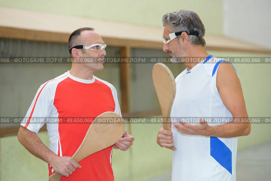 Sportmen in discussion, holding wooden rackets. Стоковое фото, агентство Ingram Publishing / Фотобанк Лори