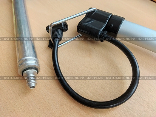 Sports tools: aluminum hand pump next to bicycle pump with support bracket. Light alloy compact pumps with attached adapters: for inflation needles, and another with a black hose for bike' nipples. Стоковое фото, фотограф Анатолий Власов / Фотобанк Лори