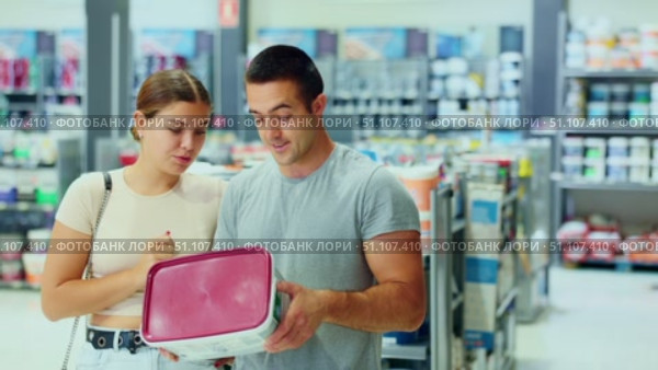 Spouses buyers with cans of paint in hands choice and closely examines product, enamel dye. Стоковое видео, видеограф Яков Филимонов / Фотобанк Лори