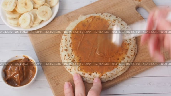 Spread thin pancakes with chocolate or cream paste. Pancakes with boiled condensed milk and banana filling. Стоковое видео, видеограф Глущенко Елена / Фотобанк Лори