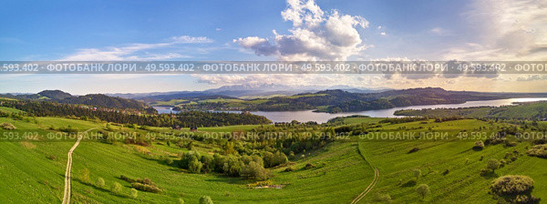 Spring mountain panorama. Lake Czorsztyn on Dunajec river. Village in green forest and meadow hills. Cloudy evening sunset sky. Aerial view of Tatra range woodland landscape. Poland, Malopolska region. Стоковое фото, агентство Ingram Publishing / Фотобанк Лори