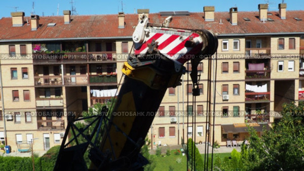 Sremska Mitrovica, Serbia 08.09.23 Hoisting crane, machines designed for movement of goods, the temporary engagement of which is carried out using lifting devices hook hangers. Multistory building (2017 год). Редакционное видео, видеограф Юлия Петровская / Фотобанк Лори