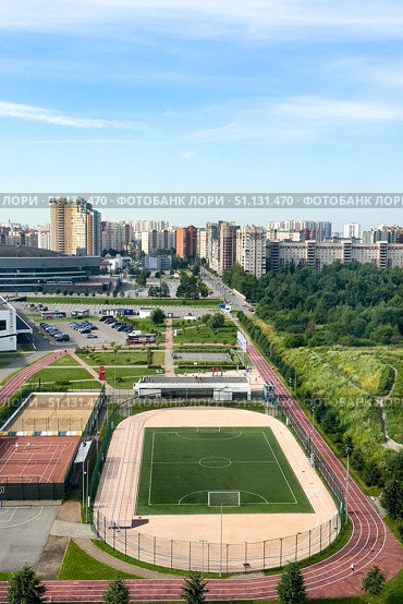 St. Petersburg, Russia - A football green field and stadium in the hockey city of St. Petersburg, surrounded by green forest and city street. Aerial view, vertical shot. Редакционное фото, фотограф Ирина Михайличенко / Фотобанк Лори
