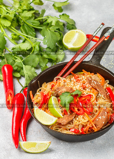 Starch (rice, potatoes) noodles with beef and vegetables - bell peppers, carrots, zucchini, sesame seeds, lime, chili, cilantro and soy sauce. A delicious dinner in the Asian style. Стоковое фото, фотограф Виктория Панченко / Фотобанк Лори
