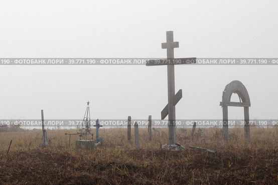 Старое кладбище в сельской местности. Большой деревянный крест и могилы в тундре. Туманная осенняя погода. Окрестности заброшенного поселка Новостройка, Магаданская область, Сибирь, Россия. Стоковое фото, фотограф Андрей Степанов / Фотобанк Лори