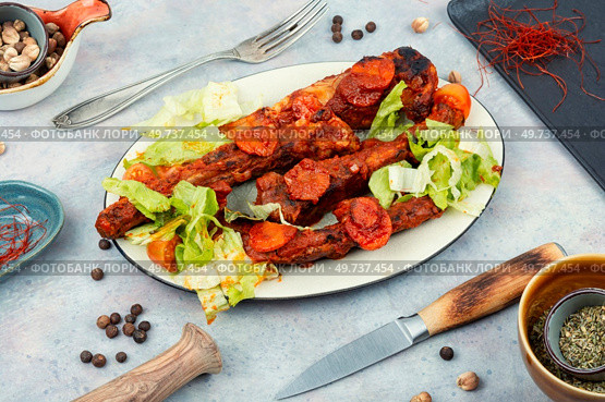 Stewed, roasted pork ribs with tomato sauce in white plate. BBQ.. Tasty stewed pork ribs in sauce. Стоковое фото, агентство Ingram Publishing / Фотобанк Лори