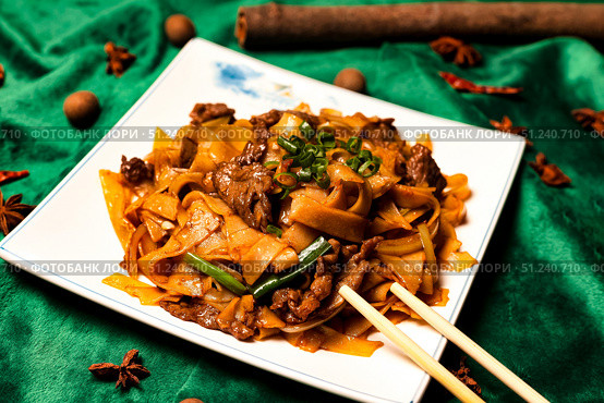 Stir Fried Rice Noodles With Beef Presentation on Vibrant Green Silk Fabric. Стоковое фото, фотограф Aleksandr Golubev / Фотобанк Лори