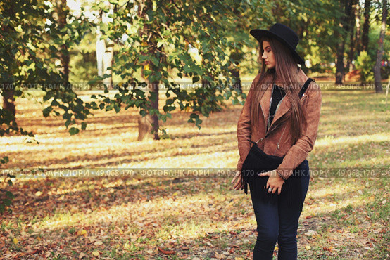 Street fashion concept - closeup portrait of a pretty girl. Wearing hat and suede jacket holding bag with fringe. Beautiful autumn woman. . Стоковое фото, агентство Ingram Publishing / Фотобанк Лори