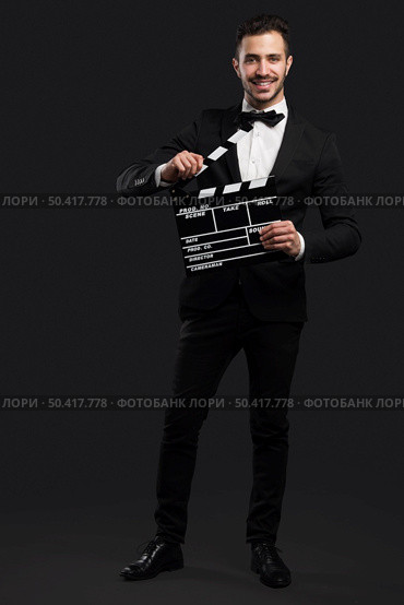 Studio portrait of a fashion young man wearing a suit and holding a clapboard. Стоковое фото, агентство Ingram Publishing / Фотобанк Лори