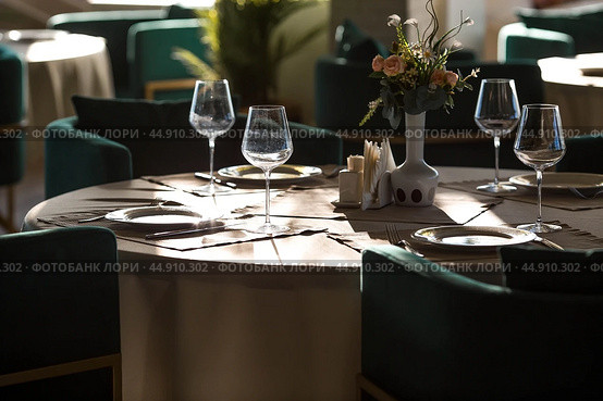 Stylish table setting. Glass glasses, plates, cutlery on the table. Wedding service, reception at the dining table. A birthday, a baptism, a festive event. Стоковое фото, фотограф Photojuli / Фотобанк Лори
