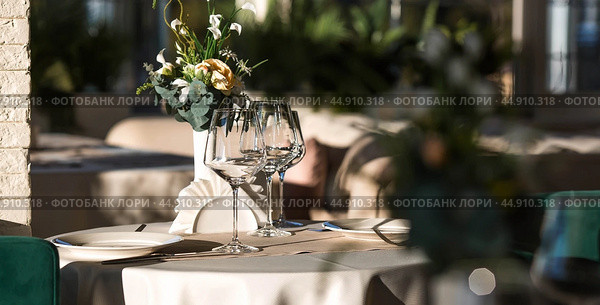 Stylish table setting. Glass glasses, plates, cutlery on the table. Wedding service, reception at the dining table. A birthday, a baptism, a festive event. Стоковое фото, фотограф Photojuli / Фотобанк Лори
