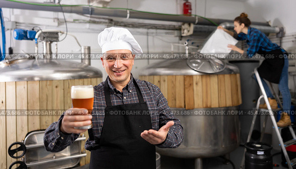 Successful brewmaster holding glass of foamy pale ale. Стоковое фото, фотограф Яков Филимонов / Фотобанк Лори