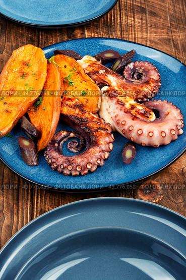 Succulent grilled octopus plated with baked sweet potato on rustic wooden table. Seafood.. Grilled octopus with vegetables. Стоковое фото, агентство Ingram Publishing / Фотобанк Лори