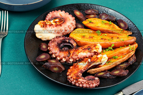 Succulent grilled octopus plated with baked sweet potato. Seafood.. Grilled octopus with vegetables. Стоковое фото, агентство Ingram Publishing / Фотобанк Лори