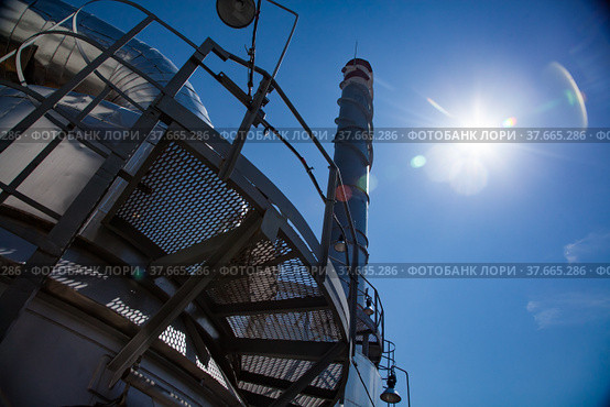 Sulphuric acid plant. Furnace for sulfur burning for dioxide and smoking stack (plant chimney). Close-up. Blue sky with sun background. Kzylorda region, Kazakhstan. Стоковое фото, фотограф Alexey Rezvykh / Фотобанк Лори