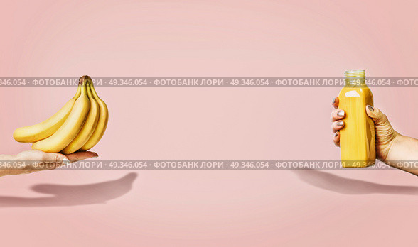 Summer food and beverages background with bananas and yellow drink bottle in female hand at pastel pink background, front view, banner or template. Стоковое фото, агентство Ingram Publishing / Фотобанк Лори