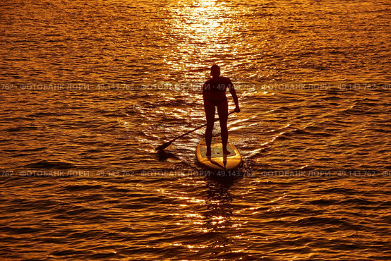 SUP Stand up Surf girl with paddle at sunset. Стоковое фото, агентство Ingram Publishing / Фотобанк Лори