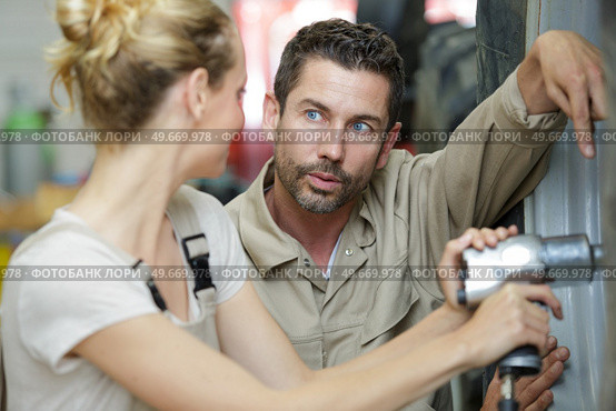supervisor questioning female mechanic using pneumatic impact wrench. Стоковое фото, агентство Ingram Publishing / Фотобанк Лори