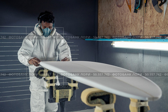 Surfboard manufacturing, Shaper working on board details. Concept of industrial manufacturing, qualified professional, occupation and employment. Стоковое фото, агентство Ingram Publishing / Фотобанк Лори