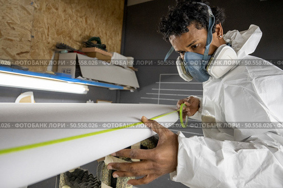Surfboard manufacturing, Shaper working on board details. Concept of industrial manufacturing, qualified professional, occupation and employment. Стоковое фото, агентство Ingram Publishing / Фотобанк Лори
