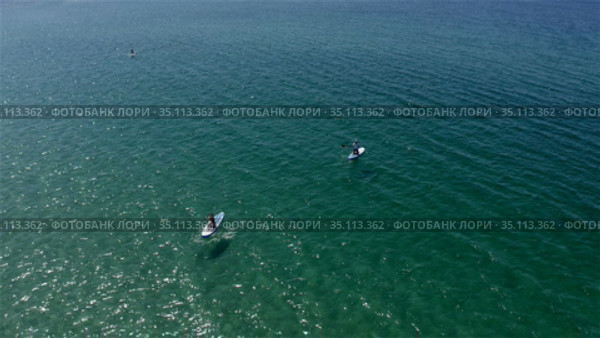 surfers slowly row on the emerald sea. Стоковое видео, видеограф Aleksandr Sulimov / Фотобанк Лори