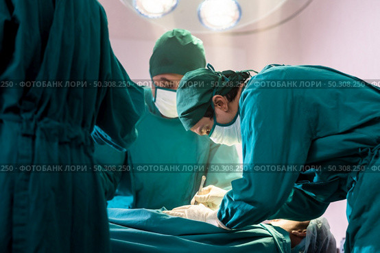 Surgeon doctor and nurse performing Surgical Operation to patient with his team in Operating Room OR. Medical health care Surgery concept. Стоковое фото, агентство Ingram Publishing / Фотобанк Лори