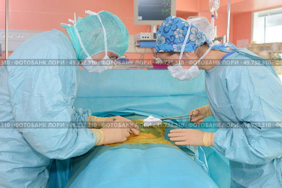 surgeons operate on a patient in the background surgical lamp. Стоковое фото, агентство Ingram Publishing / Фотобанк Лори