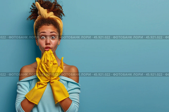 Surprised woman with curly hair and yellow cleaning gloves on blue background. Стоковое AI-изображение, AI-художник Zakharova Natasha / Фотобанк Лори