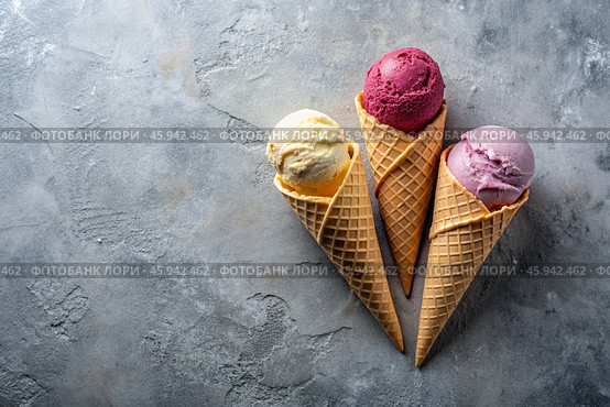 Sweet dessert. Ice cream cones with different flavors on a concrete gray background. World Ice Cream Day. Стоковое AI-изображение, AI-художник Photojuli / Фотобанк Лори